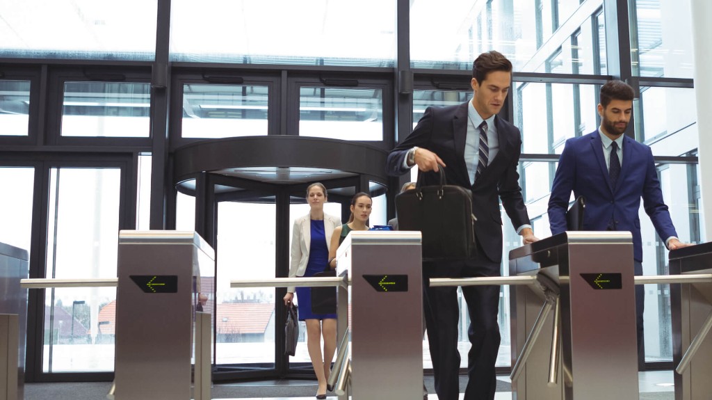 Pessoas acessando o lobby de um edifício corporativo por catracas